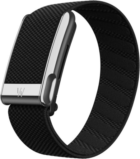 Le capteur connecté WHOOP 5.0 avec son bracelet noir posé à côté de sa batterie de recharge sans fil.
