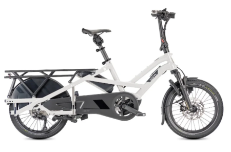 Un vélo cargo électrique tern gsd s10 transportant deux enfants sur une piste cyclable urbaine ensoleillée.