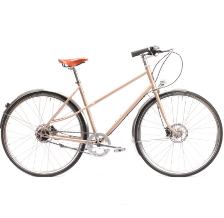 Un pelago capri turquoise garé devant une devanture moderne mettant en valeur sa ligne élégante et sa selle en cuir Brooks.