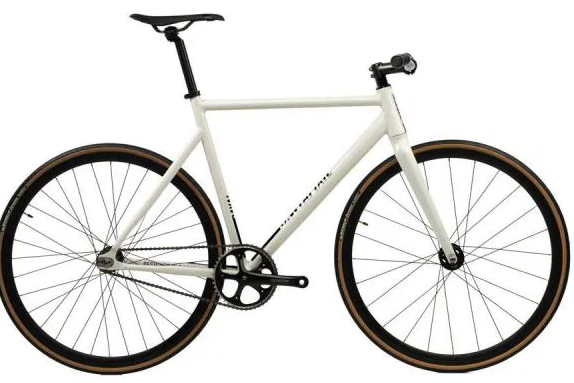 Un santafixie raval au design épuré circulant rapidement sur une piste cyclable urbaine moderne.