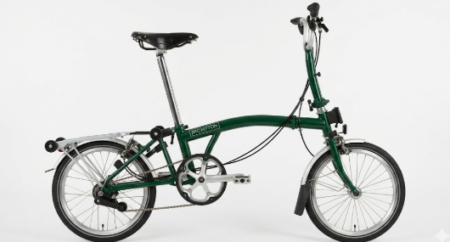 Un brompton c line plié sur un trottoir urbain mettant en avant son design compact et sa robustesse.