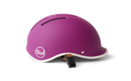 Un cycliste portant un thousand helmet élégant sur un vélo urbain pour illustrer la sécurité et le style en ville.